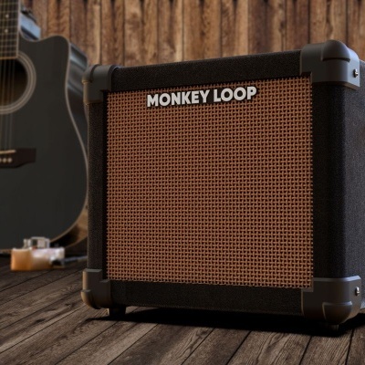 Amplificador preto MONKEY LOOP com guitarra acústica ao fundo e parede de madeira