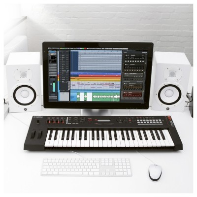 Estação de trabalho com equipamento de produção musical incluindo monitor, teclado MIDI e altifalantes brancos