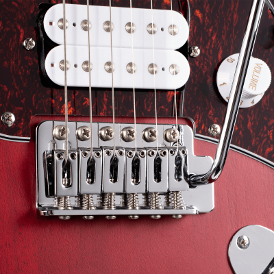 Detalhe de ponte, captadores e botão de volume de uma guitarra elétrica vermelha