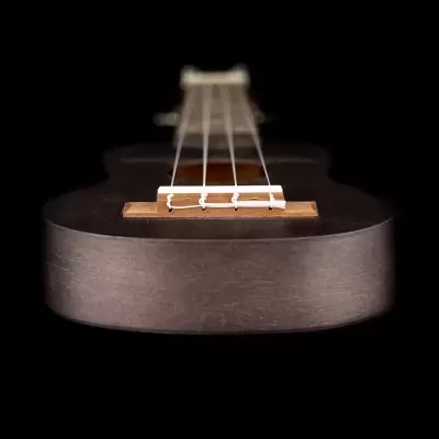 Ukulele de madeira escura com quatro cordas em fundo preto