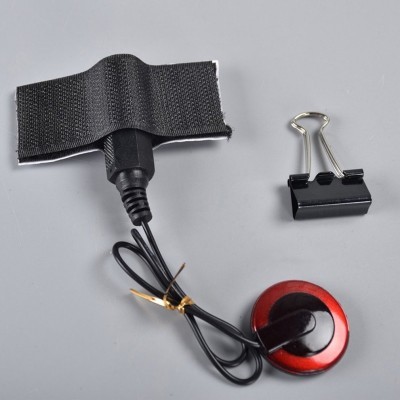 Dispositivo com faixa de velcro e clipe de papel preto sobre superfície cinzenta