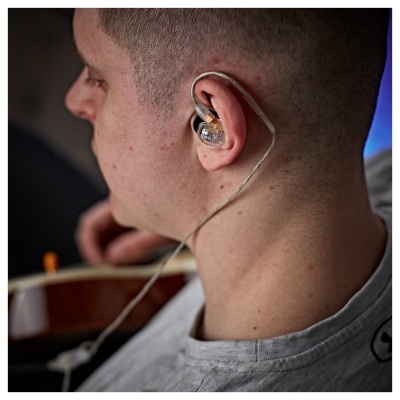 Auricular transparente intra-auricular com cabo prateado no ouvido de um homem com cabelo curto.