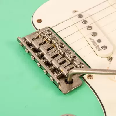 Detalhe da ponte e cordas de guitarra elétrica verde claro com captadores brancos