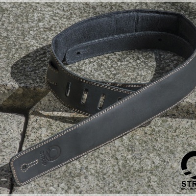 Correia preta de guitarra em couro sobre pedra cinzenta