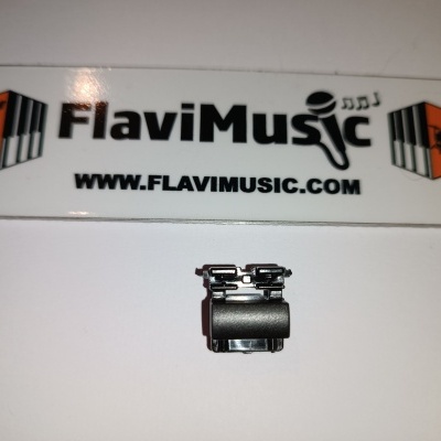 Pequeno clip metálico preto em superfície branca com cartaz FlaviMusic ao fundo