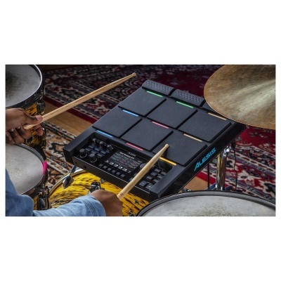 Bateria eletrónica Alesis com pads pretos sobre bateria acústica amarela