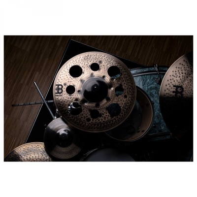 Pratos de bateria de metal com acabamento martelado e perfurações circulares sobre piso de madeira