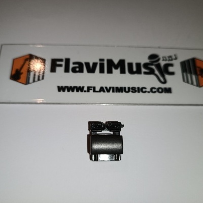 Peça pequena preta em superfície branca com cartão FlaviMusic ao fundo