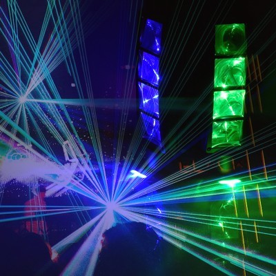 Luzes laser azuis, verdes e colunas iluminadas num ambiente escuro de discoteca