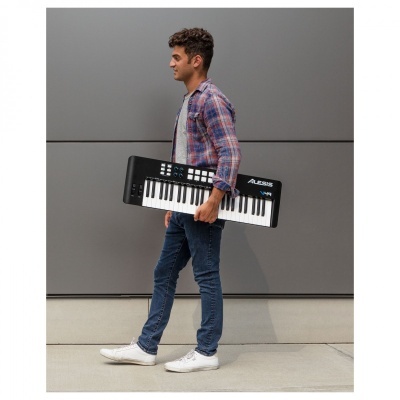 Homem jovem com camisa xadrez a carregar teclado Alesis