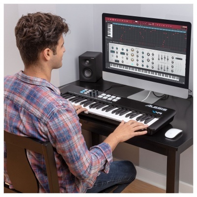 Homem toca teclado MIDI Alesis V61 preto em mesa de escritório