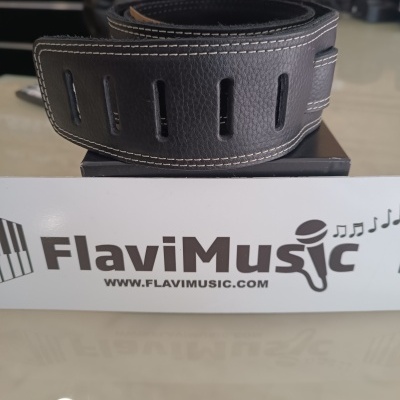 Correia preta para guitarra com costuras brancas sobre uma caixa com logotipo FlaviMusic.