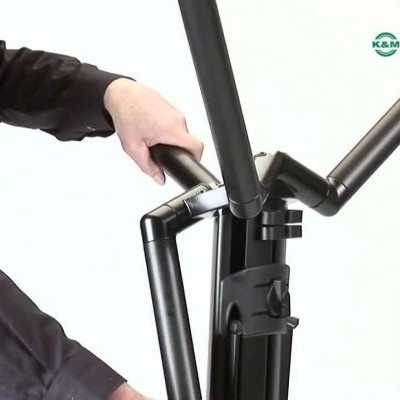 Estrutura metálica preta articulada com mãos a manipular e logotipo KÖNIG & MEYER