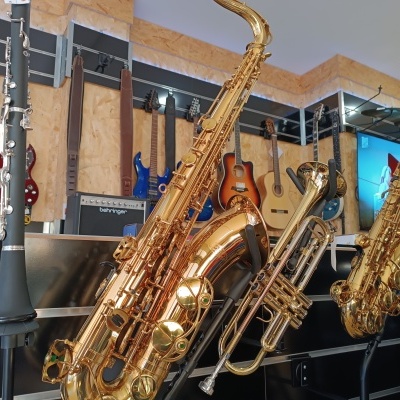Saxofones, trompete, clarinete e guitarras expostos numa loja de instrumentos musicais