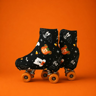 Patins de quatro rodas com capa preta decorada com temas de Halloween sobre fundo laranja