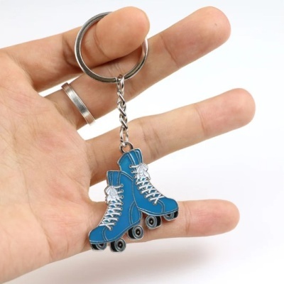 Chaveiro em forma de patins azuis segurado na mão
