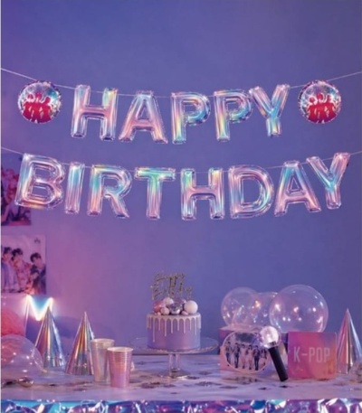 Decoração de festa com balões HAPPY BIRTHDAY metálicos e mesa com bolo e acessórios de festa em tons lilás e prateados