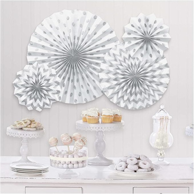 Decorações de festa em papel branco e prateado com doces numa mesa branca