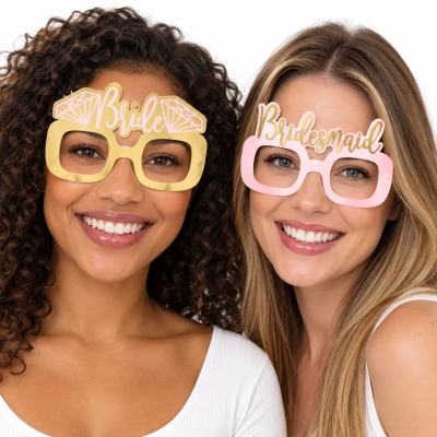 Dois óculos de festa em papel com textos Bride e Bridesmaid usados por duas mulheres sorridentes