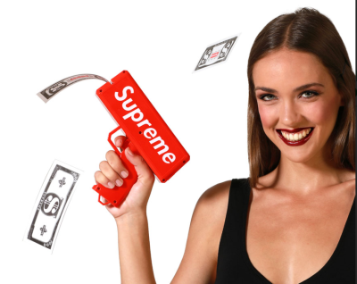 Mulher sorridente segura pistola de plástico vermelha Supreme a disparar notas falsas.