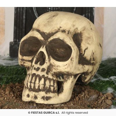 Caveira decorativa amarela com detalhes pretos sobre terra e relva