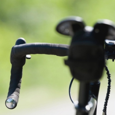 Punho do guiador de bicicleta preta embalada com fita preta e tampa metálica na extremidade