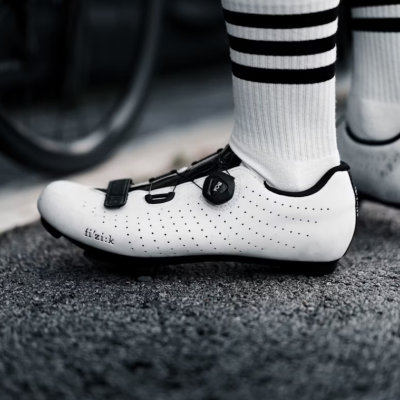 Sapatilhas de ciclismo brancas e pretas com fecho ajustável e meias brancas com riscas pretas