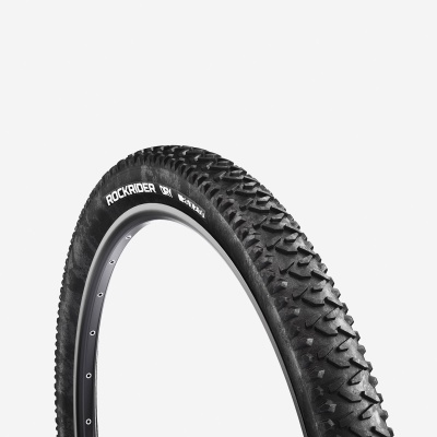 Pneu de bicicleta preto Rockrider DRY com padrão de piso agressivo em roda metálica cinza.