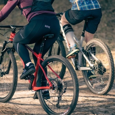 Duas bicicletas de montanha com ciclistas em terreno de terra batida.