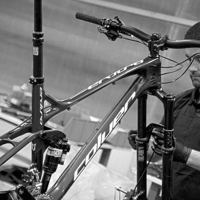 Quadro de bicicleta de montanha preta com componentes RockShox e marca COOLTECH numa oficina.