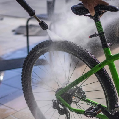 Bicicleta verde a ser lavada com jato de água pressurizada no pneu traseiro