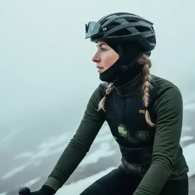 Mulher com capacete de bicicleta preto e roupa desportiva verde