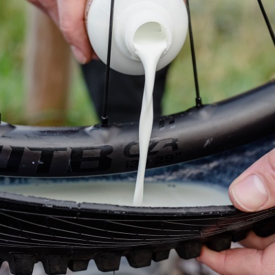 Frasco a despejar líquido branco no interior de um pneu de bicicleta preto.