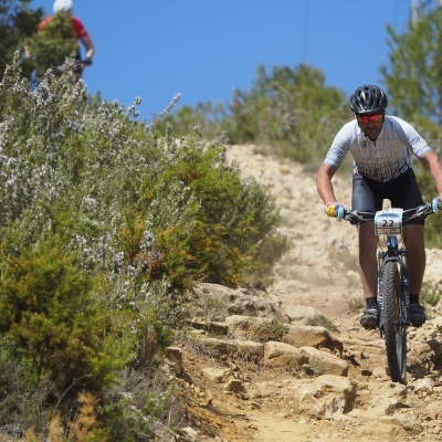 Ciclista numa bicicleta de montanha preta a descer um trilho rochoso em meio natural