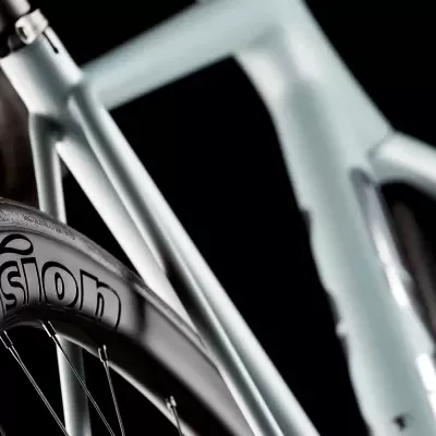 Parte lateral de bicicleta cinzenta com roda preta e texto Vision na jante