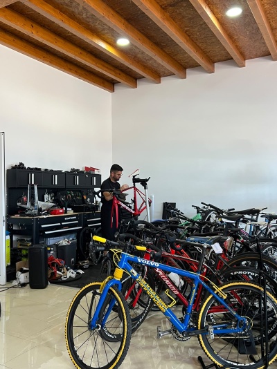 Oficina de bicicletas com várias bicicletas coloridas e homem a reparar uma bicicleta vermelha MERIDA