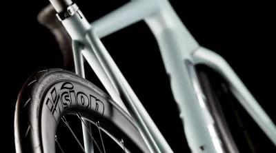 Parte lateral de bicicleta cinzenta com roda preta e texto Vision na jante