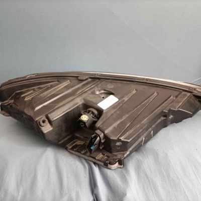 Peça automóvel de plástico preta sobre tecido azul claro