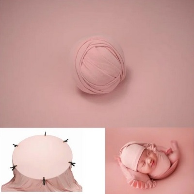 Tecido elástico cor-de-rosa para fotografia de recém-nascidos com bebé vestido e envolto no tecido.