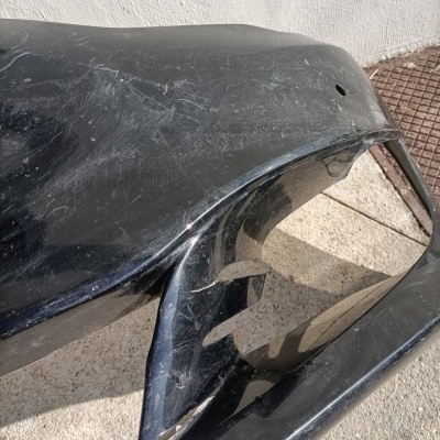 Pára-choques frontal de carro preto com riscos e marcas