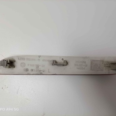 Peça automóvel branca com inscrições em relevo sobre superfície branca