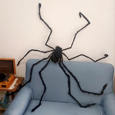 Aranha decorativa gigante preta sobre sofá azul claro