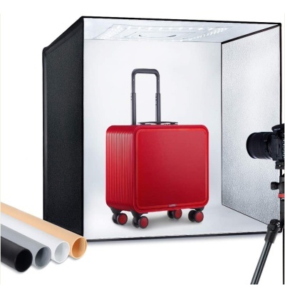 Mala de viagem vermelha com rodas dentro de caixa luminosa para fotografia