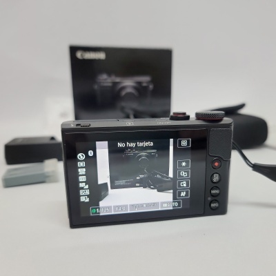 Câmara digital Canon preta com ecrã LCD a mostrar mensagem e acessórios