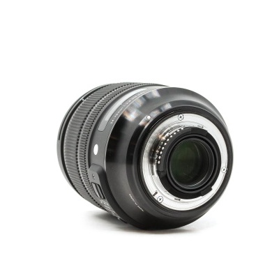 Objetiva fotográfica preta com detalhes metálicos em fundo branco