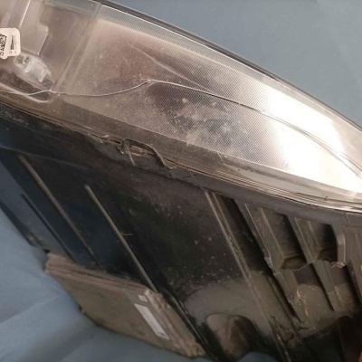 Farol automóvel Volvo com lente transparente e corpo preto seguro por mão