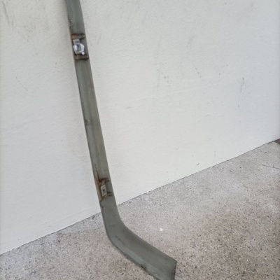 Barra metálica cinzenta encostada numa parede branca.