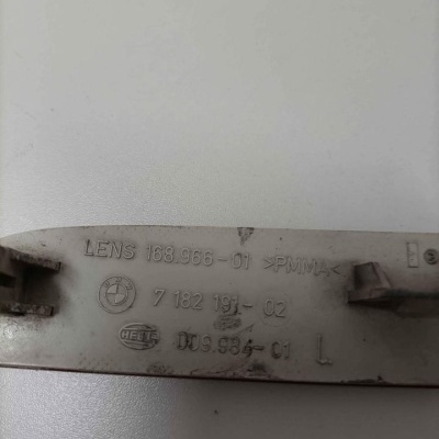 Parte traseira de peça plástica cinzenta com textos e logotipos em relevo sobre fundo branco