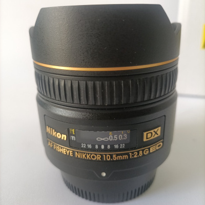 Objetiva fotográfica Nikon AF FISHEYE NIKKOR 10.5mm preta com detalhes dourados