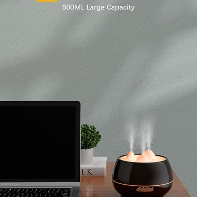 Difusor de aromas preto a libertar vapor com computador e planta ao fundo